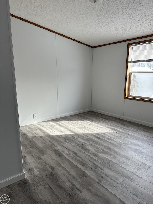 empty room featuring hardwood / wood-style floors, ornamental molding, and a textured ceiling