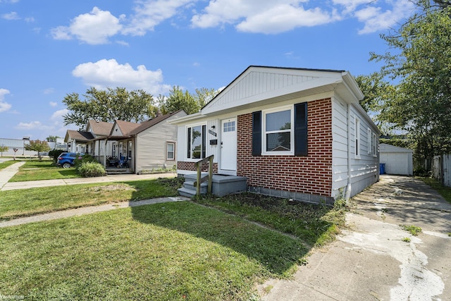 bungalow-style home with a garage, an outdoor structure, and a front lawn