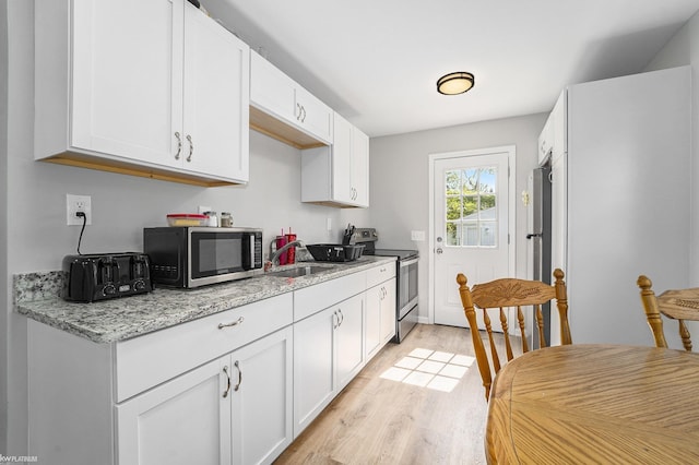 kitchen with light stone counters, stainless steel appliances, sink, and white cabinets