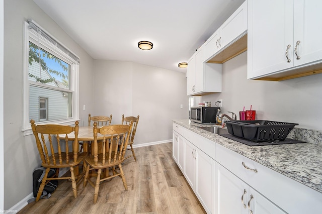 kitchen featuring light stone countertops, white cabinets, and light hardwood / wood-style floors