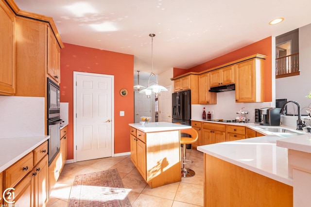 kitchen featuring pendant lighting, sink, a kitchen bar, a center island, and black appliances