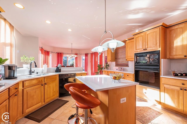 kitchen with a kitchen island, decorative light fixtures, sink, a breakfast bar area, and black appliances