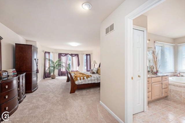 bedroom featuring light colored carpet and ensuite bathroom