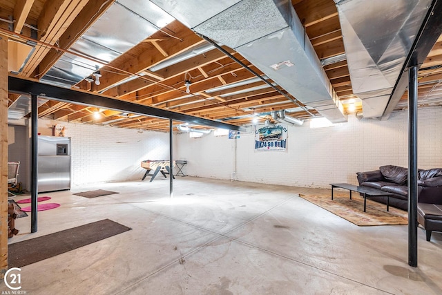 basement with brick wall and stainless steel fridge