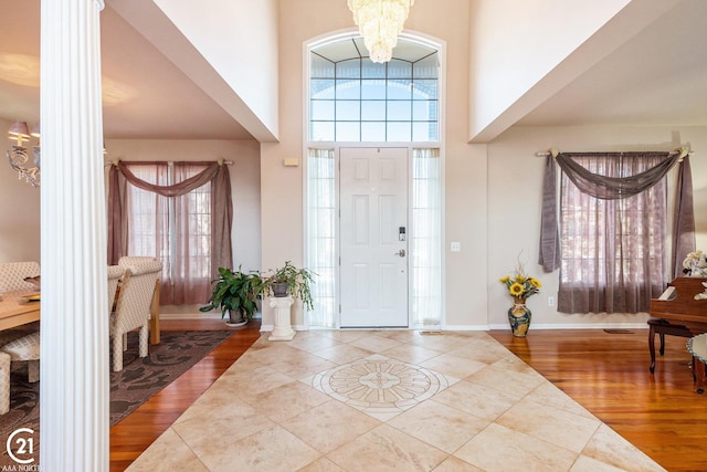 entryway with hardwood / wood-style flooring, a towering ceiling, and a notable chandelier