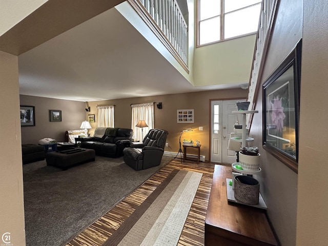 carpeted living room with a baseboard radiator and a towering ceiling