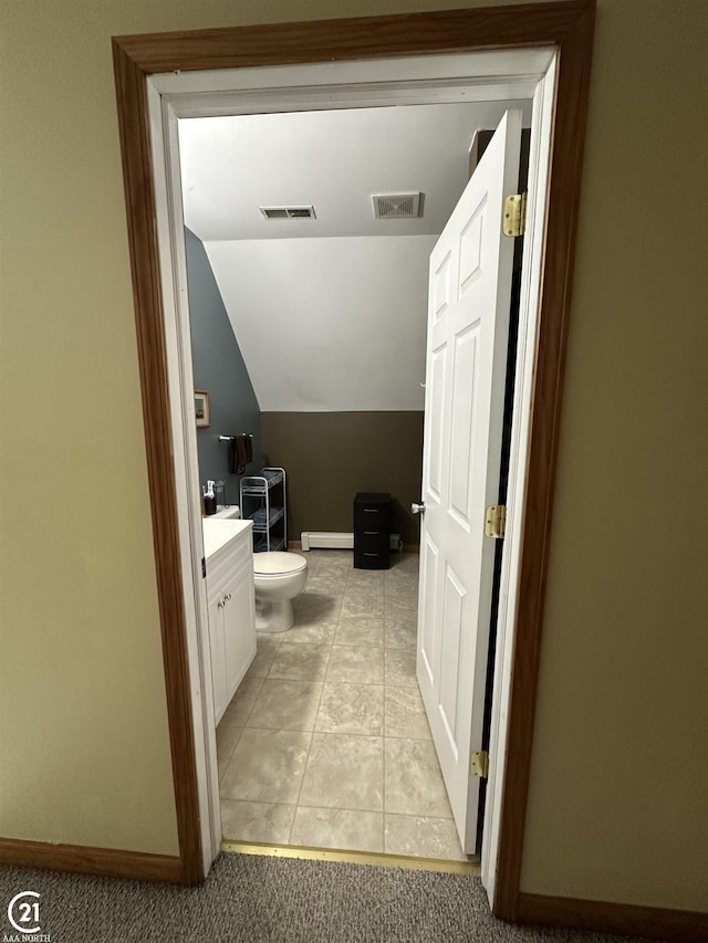 bathroom with a baseboard heating unit, vanity, vaulted ceiling, tile patterned floors, and toilet