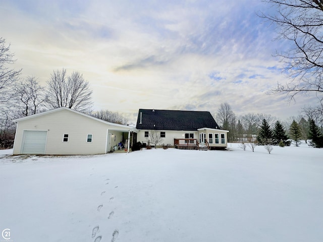 snow covered property with a wooden deck and a garage