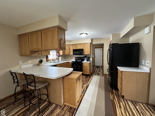 kitchen featuring kitchen peninsula, dark hardwood / wood-style flooring, and black appliances