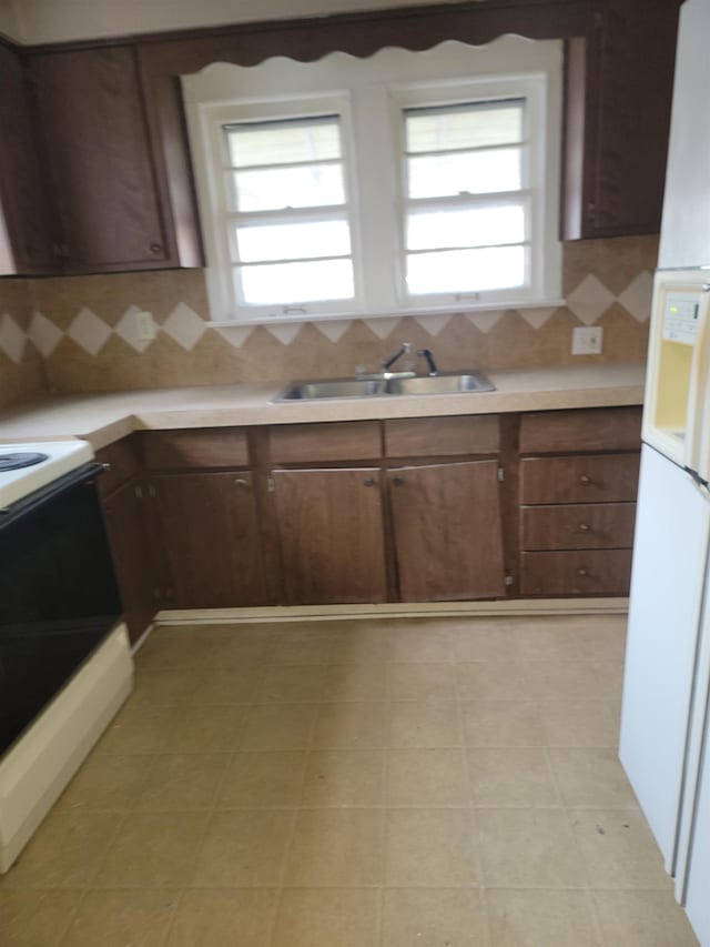 kitchen featuring tasteful backsplash, dark brown cabinetry, range, and sink