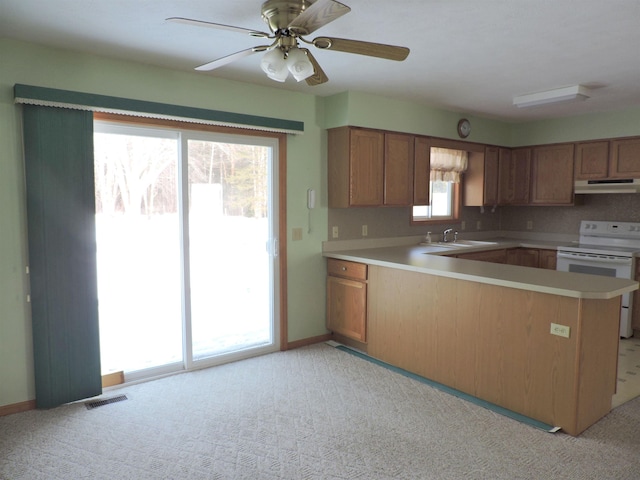 kitchen with sink, white electric range, light colored carpet, and kitchen peninsula