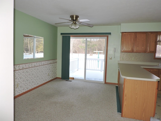 kitchen featuring ceiling fan, kitchen peninsula, and light carpet