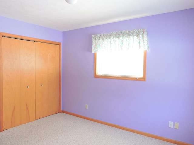 unfurnished bedroom with light carpet and a closet