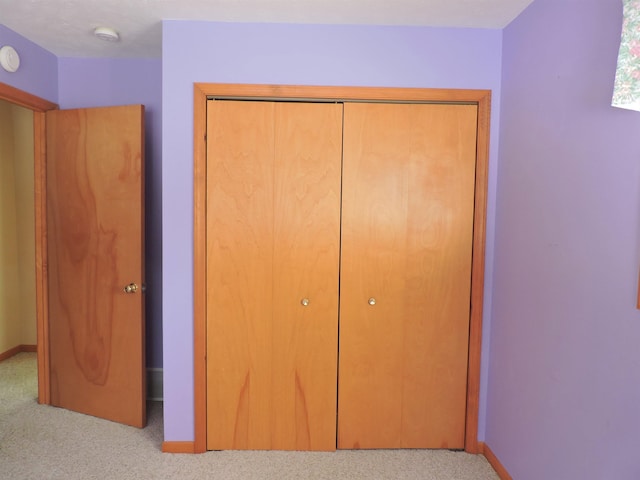 unfurnished bedroom with light carpet and a closet