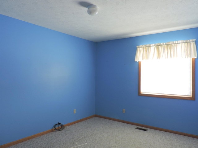 carpeted empty room with a textured ceiling