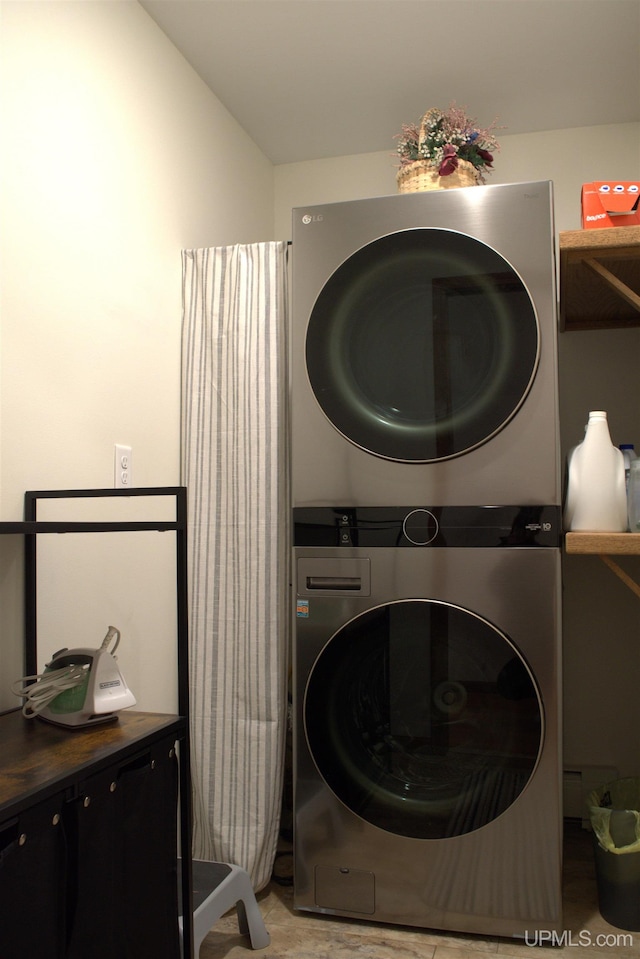 washroom featuring cabinets and stacked washer and clothes dryer