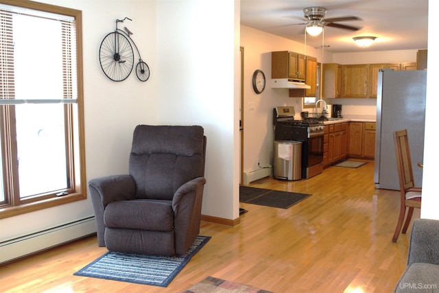 kitchen featuring appliances with stainless steel finishes, a baseboard heating unit, sink, and light hardwood / wood-style floors