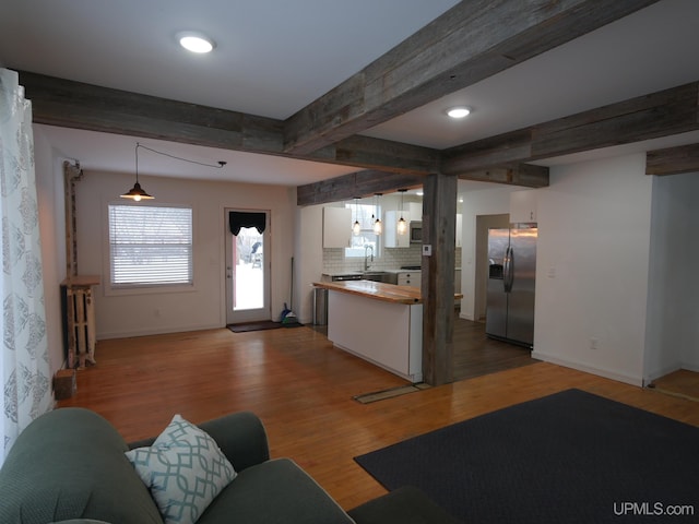 unfurnished living room with radiator, wood-type flooring, sink, and beamed ceiling