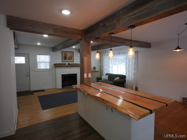 kitchen featuring dark wood-type flooring, butcher block counters, pendant lighting, beam ceiling, and white cabinets