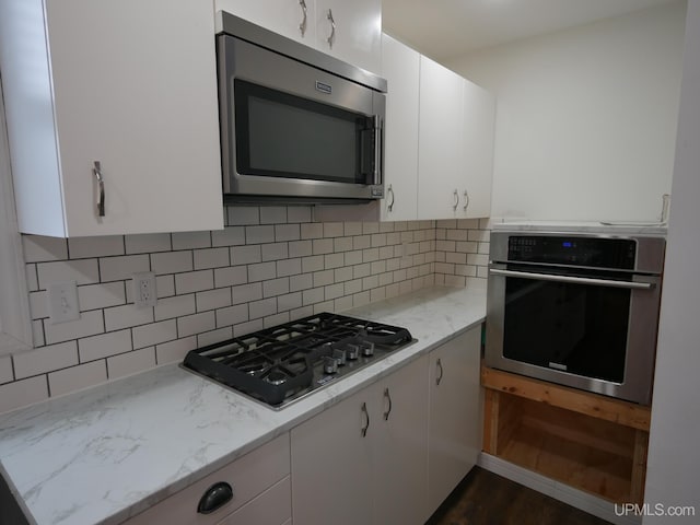 kitchen featuring white cabinetry, light stone countertops, tasteful backsplash, and stainless steel appliances