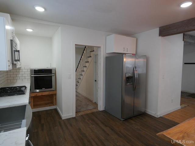 kitchen featuring tasteful backsplash, white cabinetry, appliances with stainless steel finishes, and dark hardwood / wood-style flooring