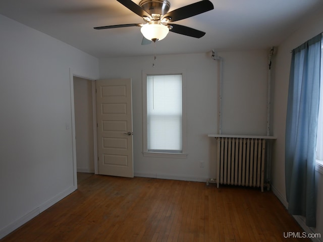 spare room featuring hardwood / wood-style floors, radiator heating unit, and ceiling fan