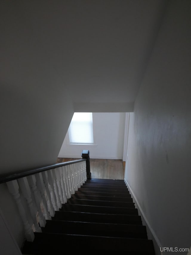 stairway featuring vaulted ceiling and hardwood / wood-style floors