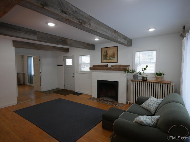 living room with beamed ceiling, a fireplace, radiator, and hardwood / wood-style floors