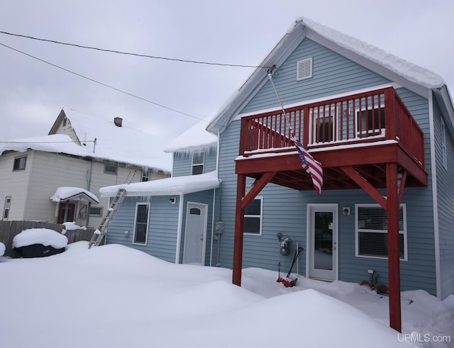 snow covered back of property featuring a wooden deck