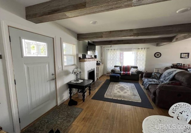 living room with beam ceiling, a fireplace, and hardwood / wood-style flooring