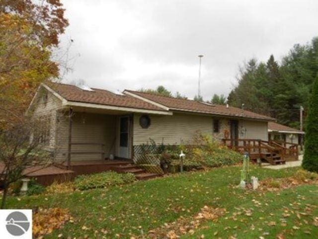 view of front of home with a deck and a front lawn