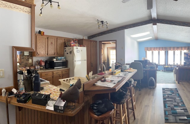 kitchen with lofted ceiling, light hardwood / wood-style flooring, white fridge, and a textured ceiling