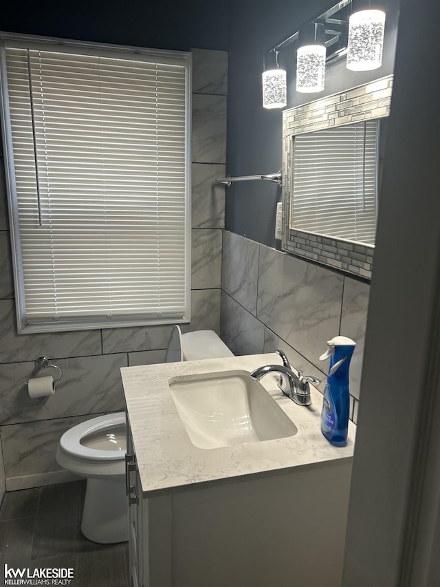 bathroom featuring vanity, toilet, and tile walls