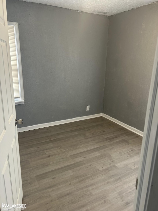 empty room featuring wood-type flooring and a textured ceiling