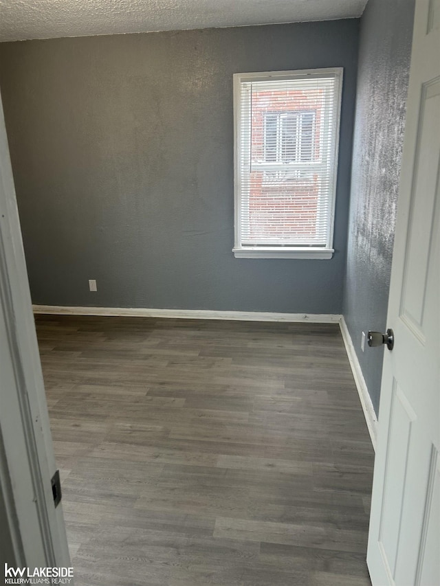 empty room featuring dark hardwood / wood-style flooring and a textured ceiling