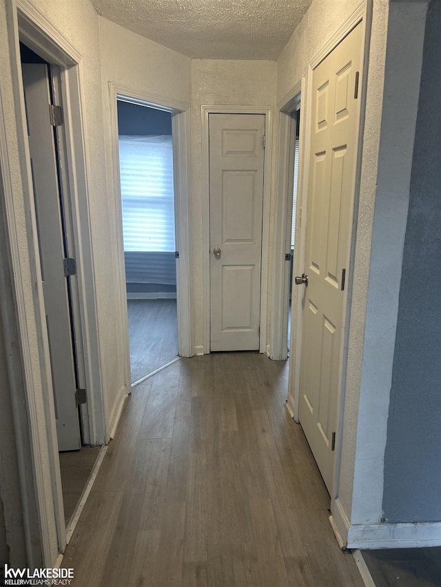 hallway with dark hardwood / wood-style floors and a textured ceiling