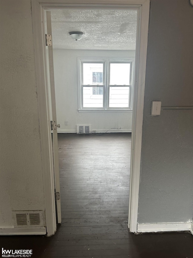 corridor featuring dark hardwood / wood-style flooring and a textured ceiling