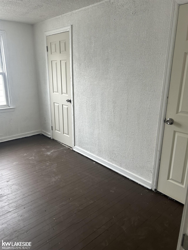 empty room with dark hardwood / wood-style flooring and a textured ceiling