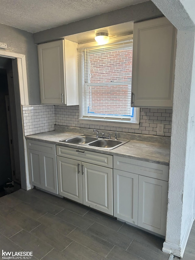 kitchen featuring white cabinetry, sink, a textured ceiling, and decorative backsplash