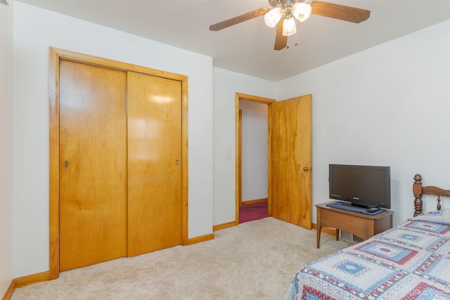 carpeted bedroom featuring ceiling fan and a closet