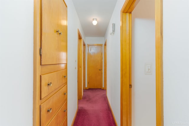 hall featuring dark colored carpet