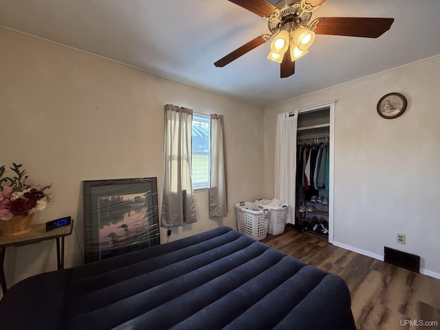 bedroom with dark wood-type flooring, ceiling fan, and a closet