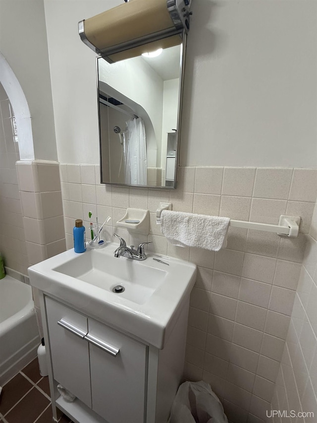 bathroom with tile patterned floors, shower / bathtub combination with curtain, vanity, and tile walls