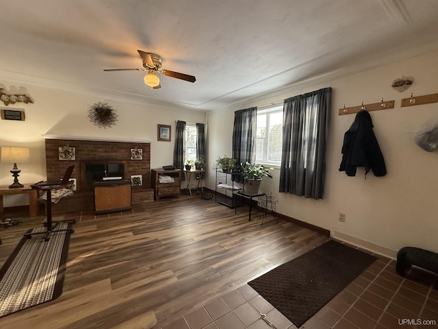 interior space with a brick fireplace, dark hardwood / wood-style floors, and ceiling fan