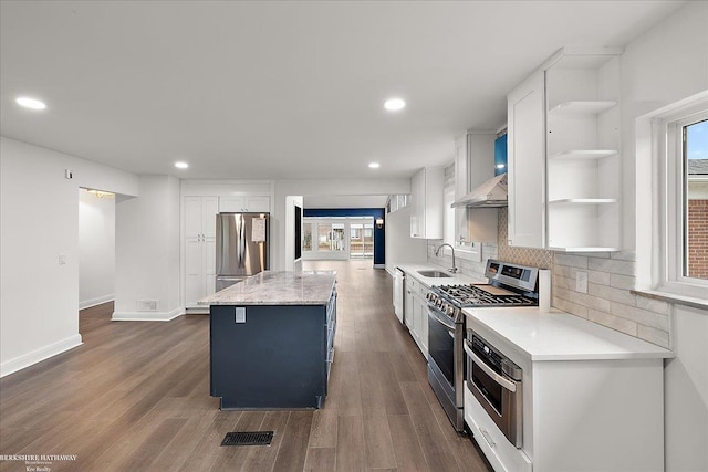 kitchen with appliances with stainless steel finishes, tasteful backsplash, sink, white cabinets, and a center island