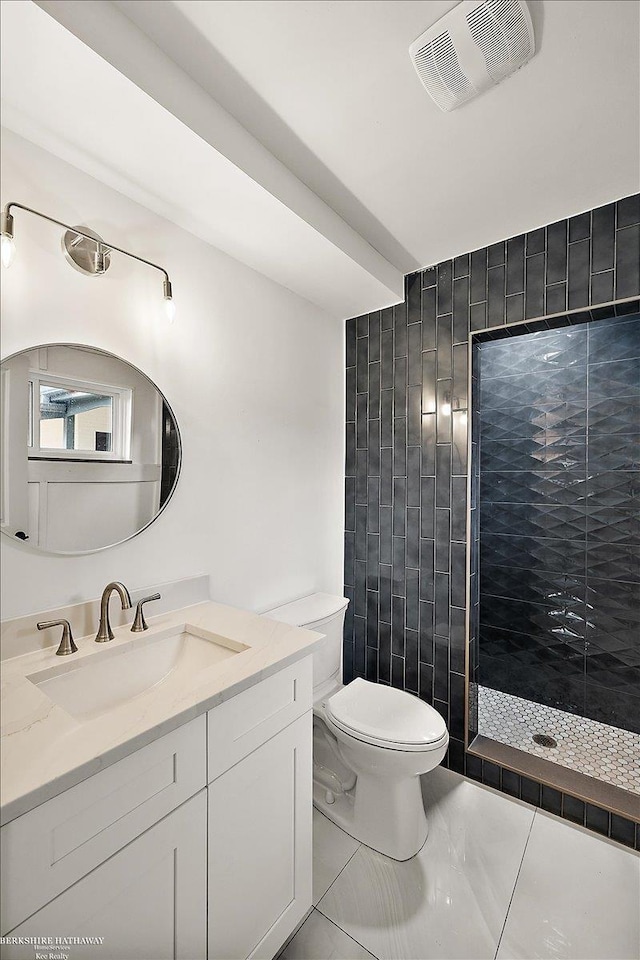 bathroom with tiled shower, vanity, and toilet