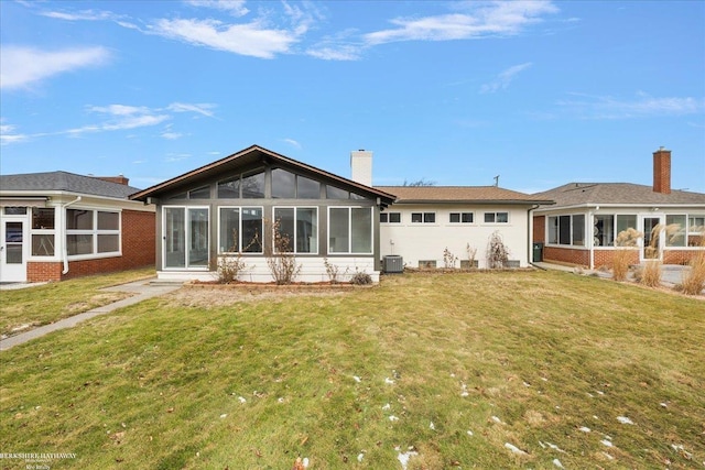 back of property featuring a sunroom, central AC unit, and a lawn