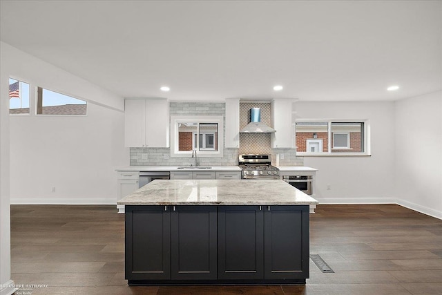 kitchen featuring tasteful backsplash, sink, white cabinets, stainless steel appliances, and wall chimney exhaust hood