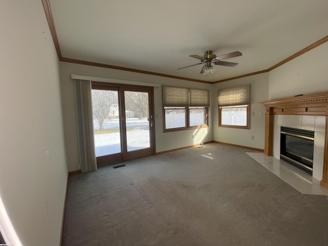 unfurnished living room featuring light colored carpet, ornamental molding, a tile fireplace, and a healthy amount of sunlight