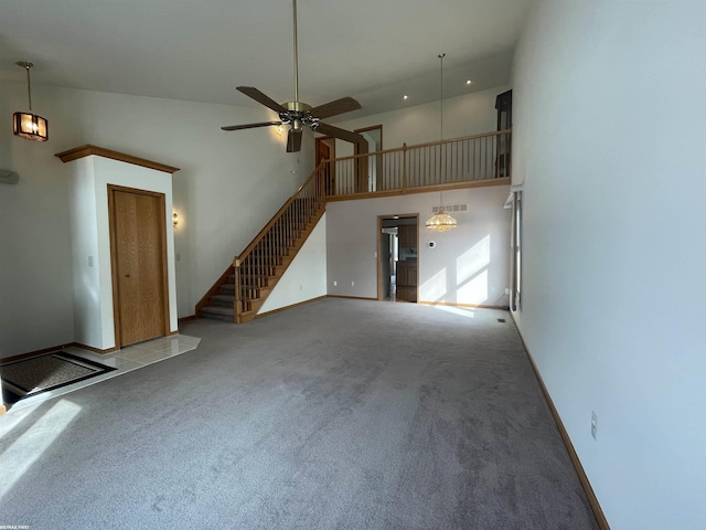 unfurnished living room with ceiling fan, light colored carpet, and a high ceiling